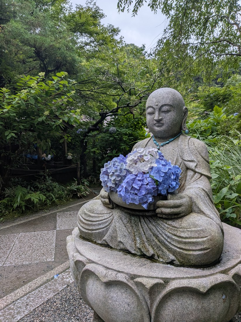 A stone Jizo holding hydrangeas